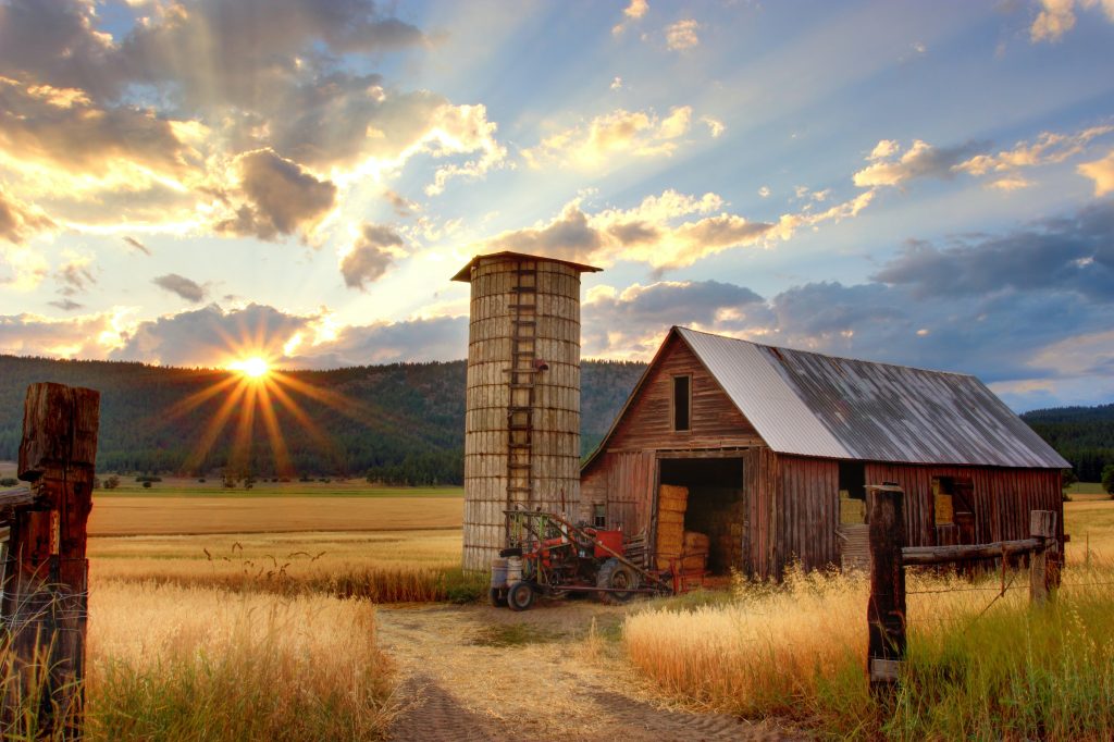 An image of a barn with a sunset behind it.